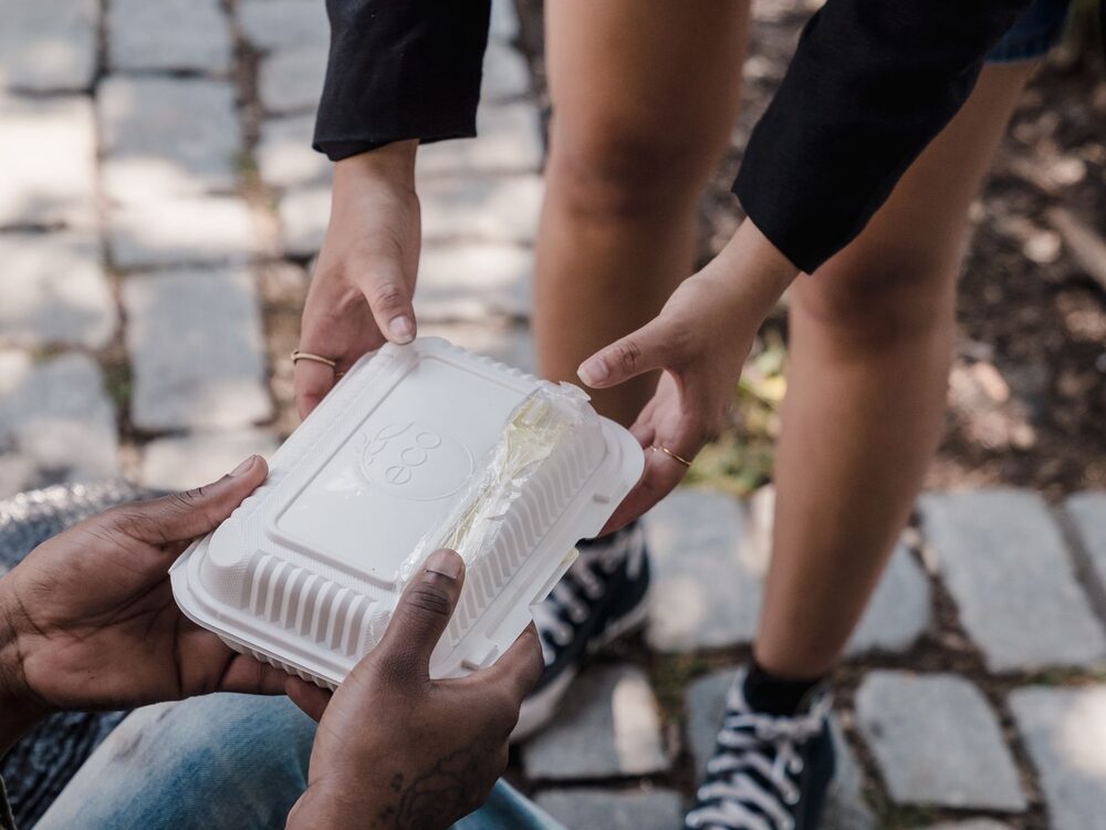Hands offering a warm meal to someone in need